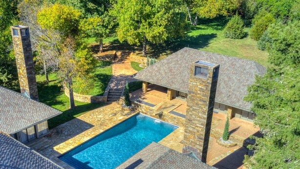 Una piscina con paredes y techo de piedra, rodeada por un jardín y árboles.