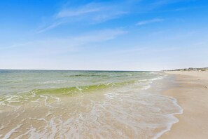 A beach with clear blue sky and calm waves. - Family Beachside Retreat: Door to Sand in Two Minutes! Six Pools (Gulf Shores)