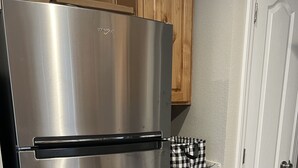 A stainless steel refrigerator in a kitchen with wooden cabinets and a marble countertop.
