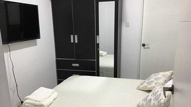 Une chambre à coucher avec un lit, une armoire et un téléviseur fixé au mur.