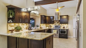 A modern kitchen with dark wood cabinets, a granite countertop, and stainless steel appliances. - Unique house - heated pool and hot tub option near Clearwater Beach Florida (Clearwater)