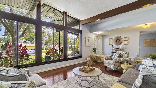 A spacious living room with large windows, a round coffee table, and a comfortable seating area. - Unique house - heated pool and hot tub option near Clearwater Beach Florida (Clearwater)