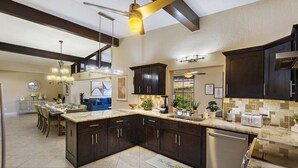 A modern kitchen with dark cabinetry, a large island, and a built-in dishwasher. - Unique house - heated pool and hot tub option near Clearwater Beach Florida (Clearwater)