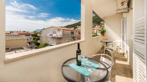 Un balcón con una mesa, una botella de vino y vistas de la ciudad.