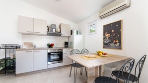 Una cocina moderna con armarios blancos, una mesa de comedor de madera y sillas negras.