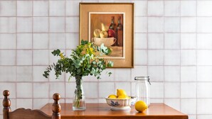 Ein Holztisch mit einer Blumenvase, einer Zitronenschale und einem Glas.