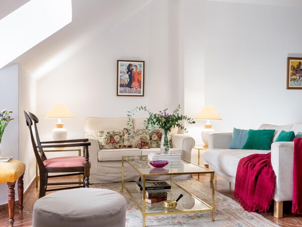Una sala de estar con un sofá, dos sillones, una mesa de centro y un cuadro en la pared.
