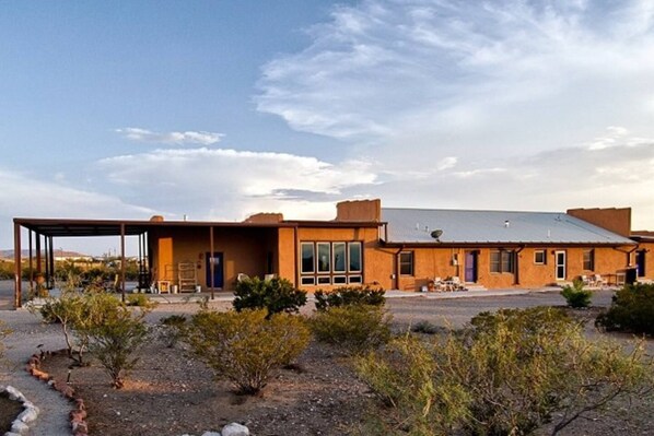 A modern two-story building with a covered patio area, large windows, and a flat roof.
