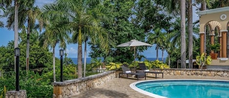 Alberca al aire libre, sombrillas en la alberca y camastros