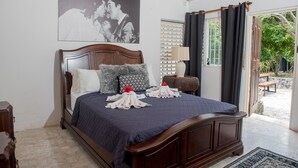 A neatly made bed with a dark blue bedspread and pillows, a wooden headboard, and a large framed picture on the wall. - Music Mansion (Montego Bay)