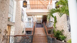 A staircase with ornate metal railings, a stone wall, and a statue. - Music Mansion (Montego Bay)