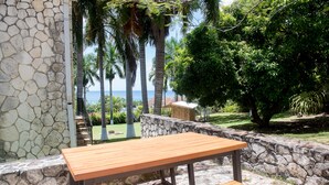 A stone wall with a wooden bench and a view of the ocean. - Music Mansion (Montego Bay)