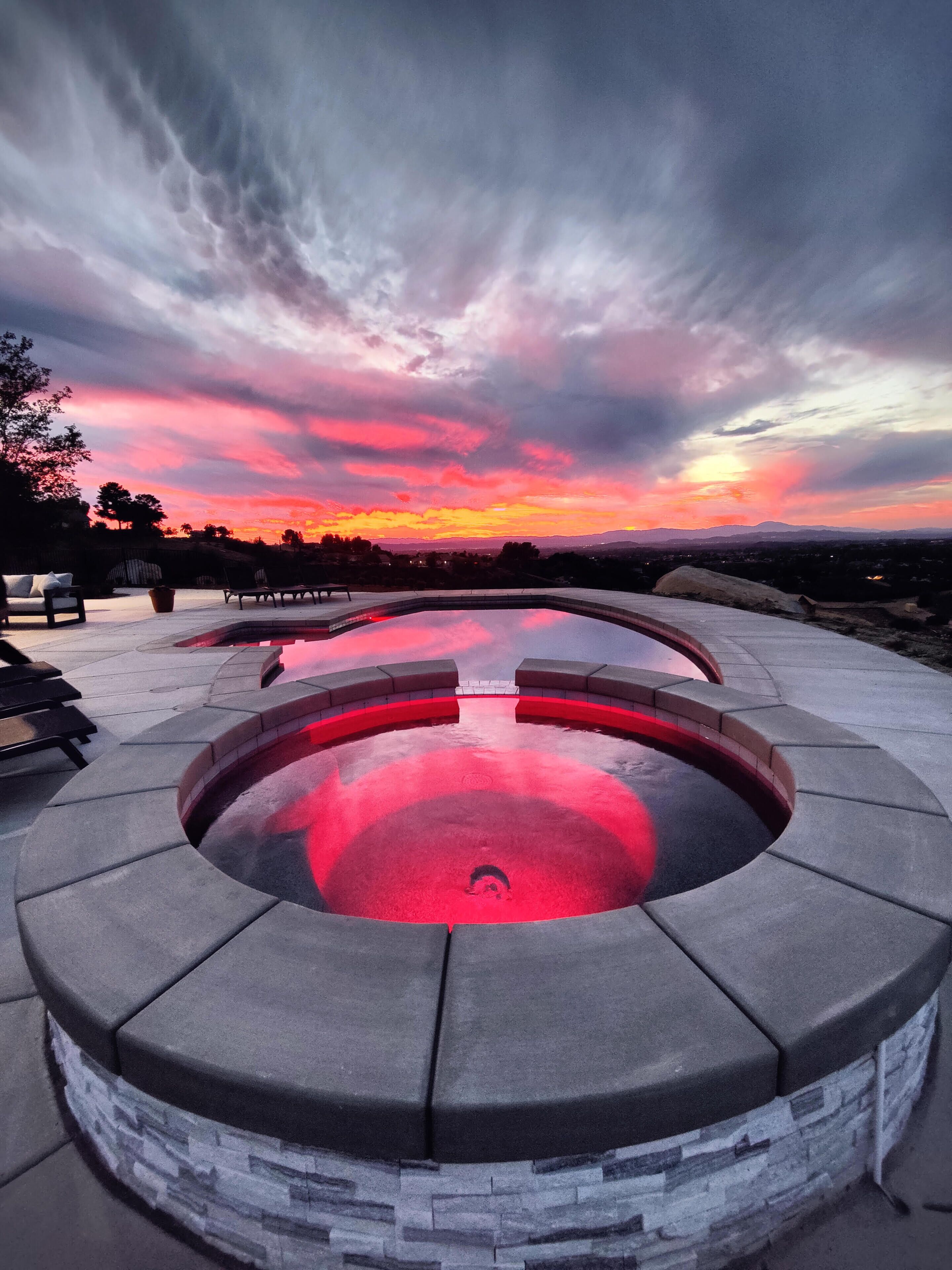 Een verwarmd zwembad, ligstoelen bij het zwembad