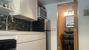 Een moderne keuken met witte kastjes, een inbouwvaatwasser, een magnetron en een betegelde achterwand.