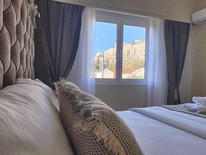 Una habitación de hotel con cama, ventana con cortinas y vistas a un edificio.