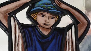 A stained glass window with a figure in a blue robe and a hat.