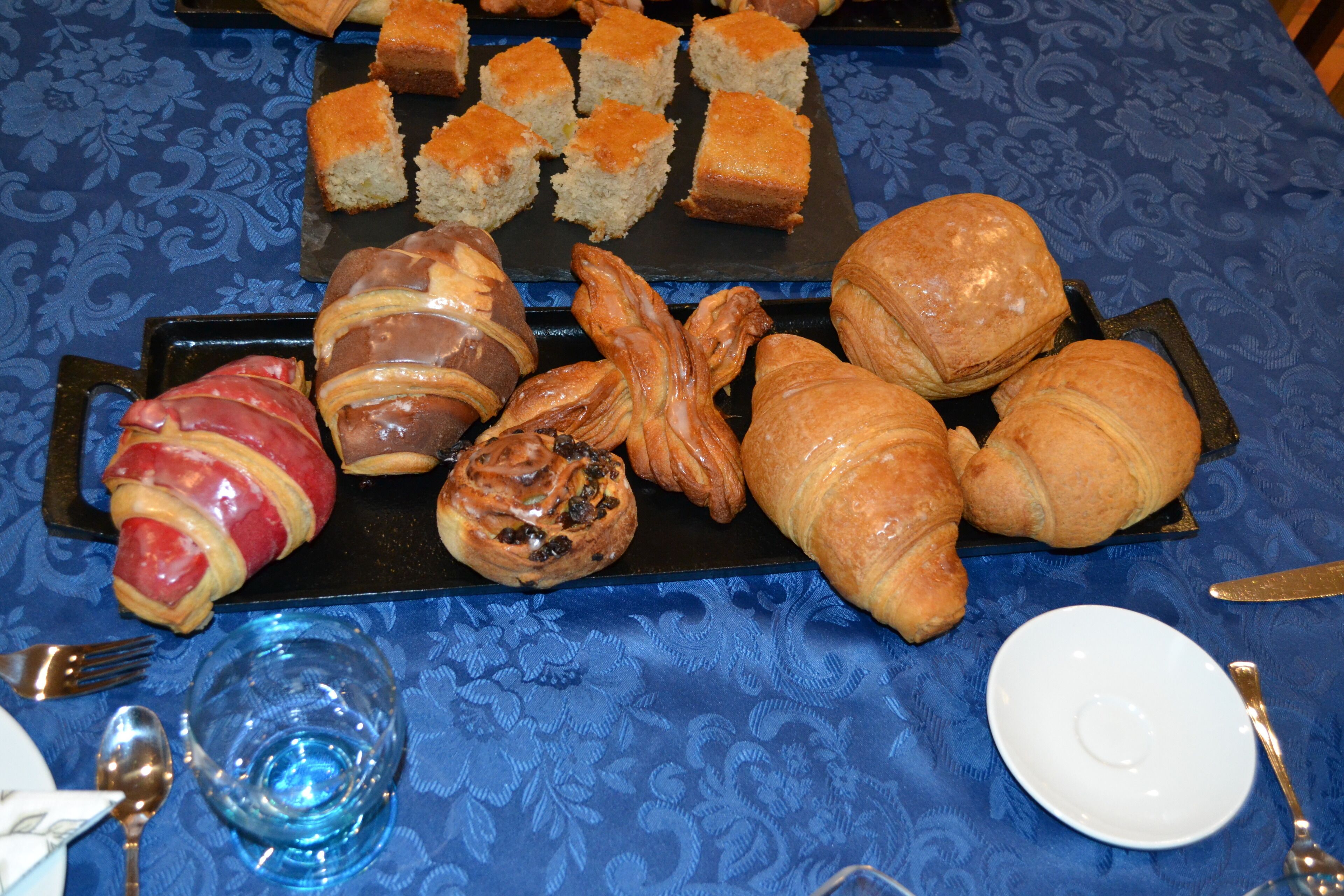 A table with various pastries and bread, including croissants and a pastry wrapped in bacon.