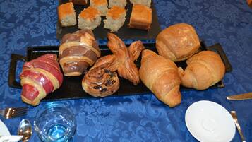 A table with various pastries and bread, including croissants and a pastry wrapped in bacon.