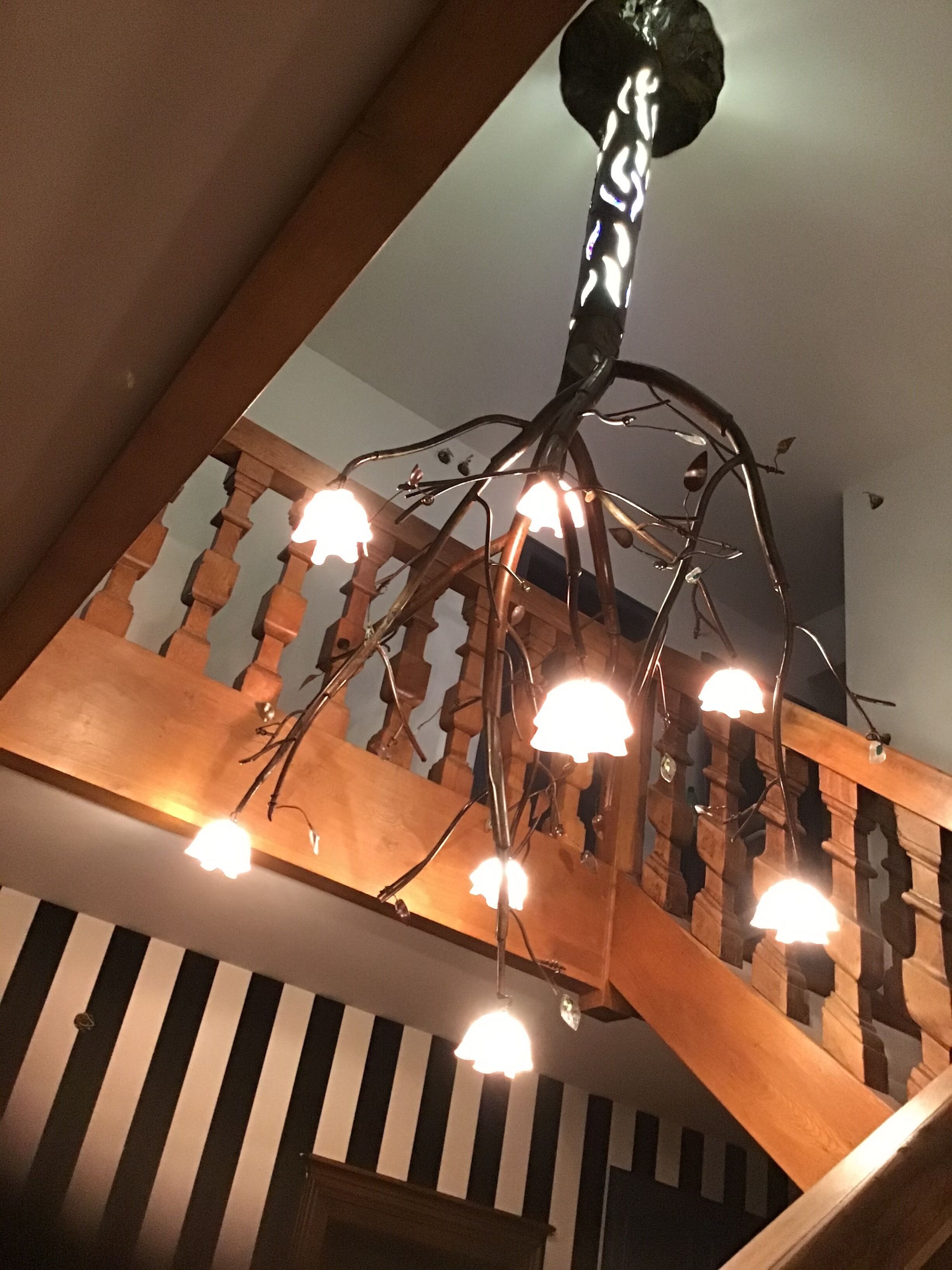 A wooden staircase with a unique metal chandelier.