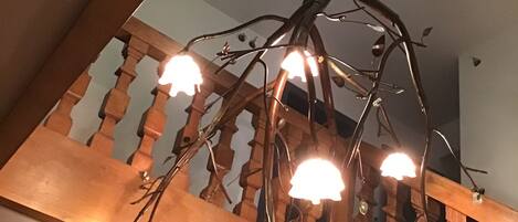 A wooden staircase with a unique metal chandelier.