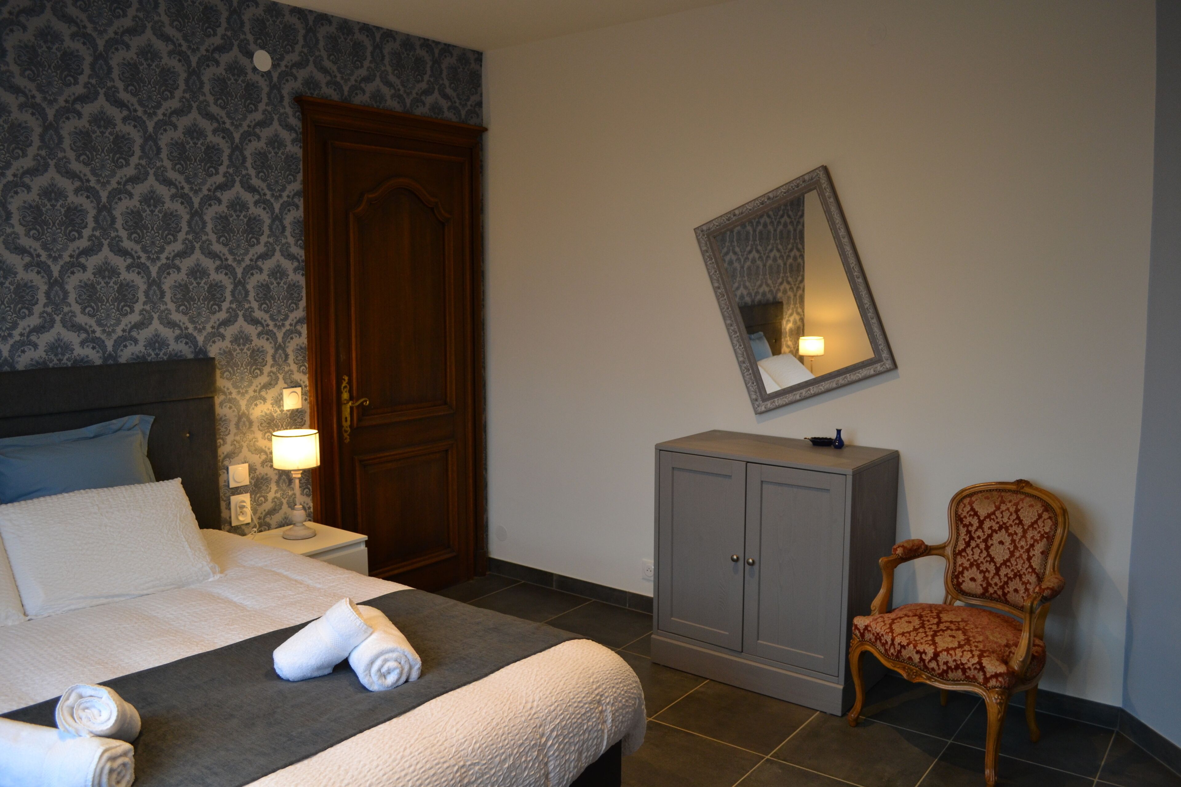 Ett hotellrum med en säng, en garderob, en stol och en spegel på väggen.
