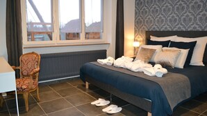 Une chambre d’hôtel avec un lit, une chaise, une table et une fenêtre donnant sur des immeubles.