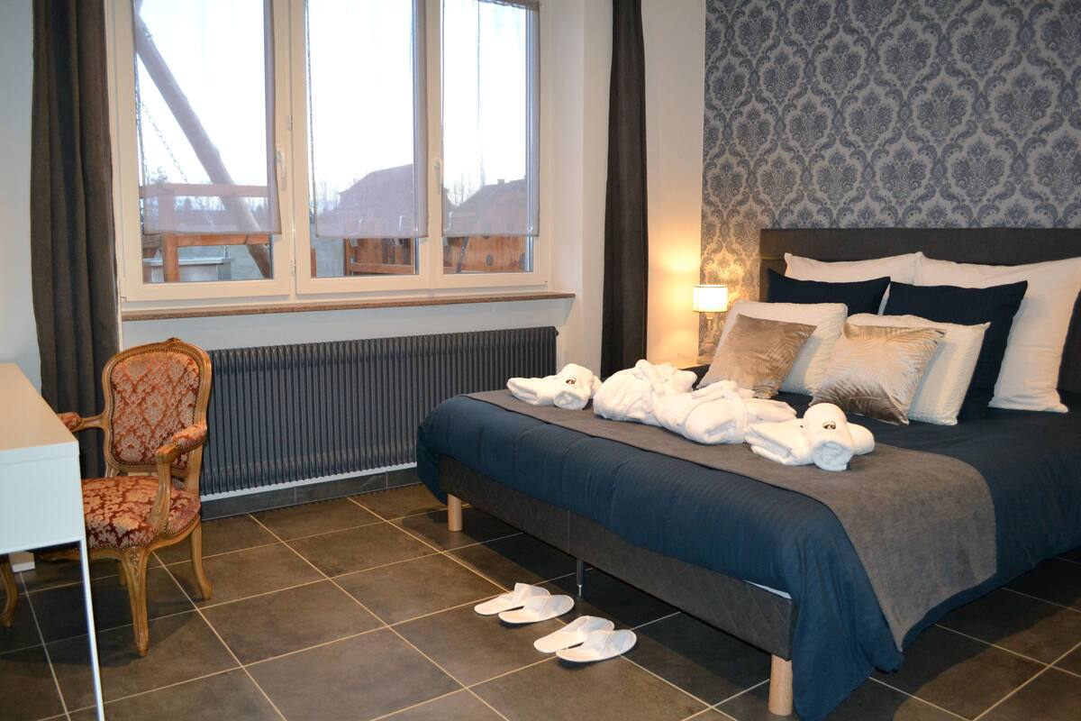 Une chambre d’hôtel avec un lit, une chaise, une table et une fenêtre donnant sur des immeubles.