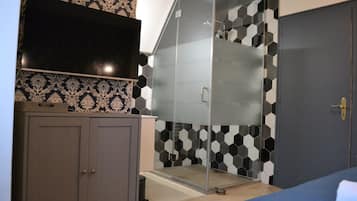 A bedroom with a bed, a wardrobe, a TV, and a shower area with a glass door.