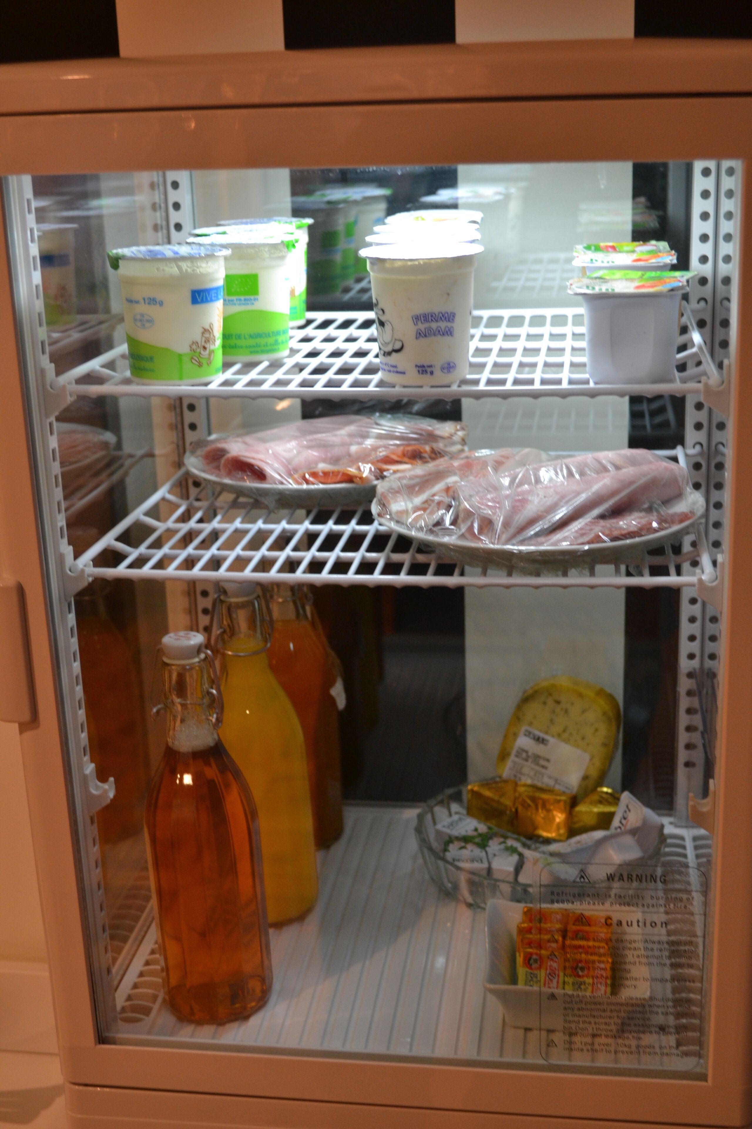 Un présentoir réfrigéré contenant des produits laitiers, des viandes emballées et des condiments.