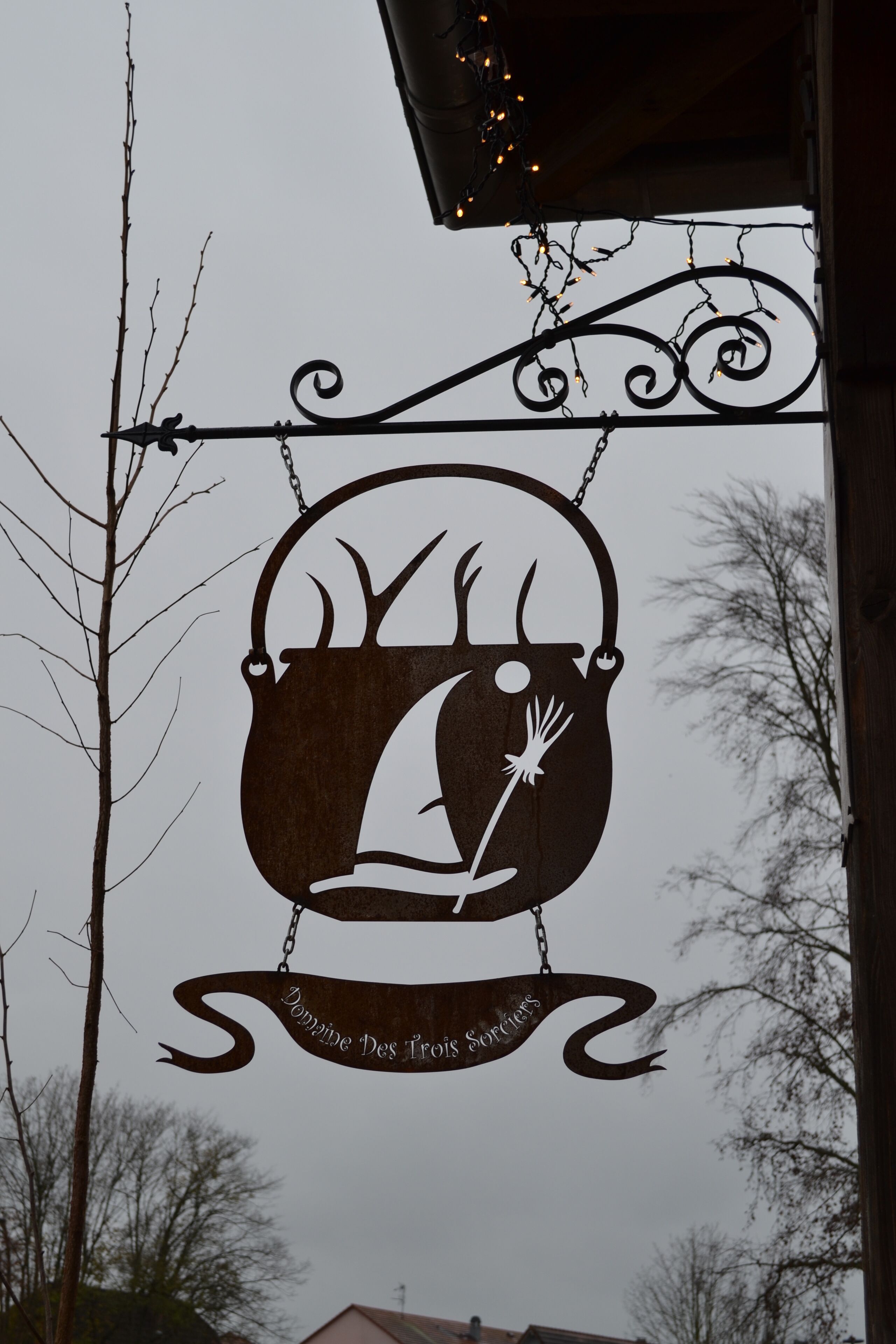 A sign with a bear and a fish, hanging from a metal fixture.