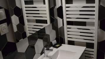 A bathroom with a white sink, a mirror, and a towel rack. The wall has a black and white hexagonal tile pattern.
