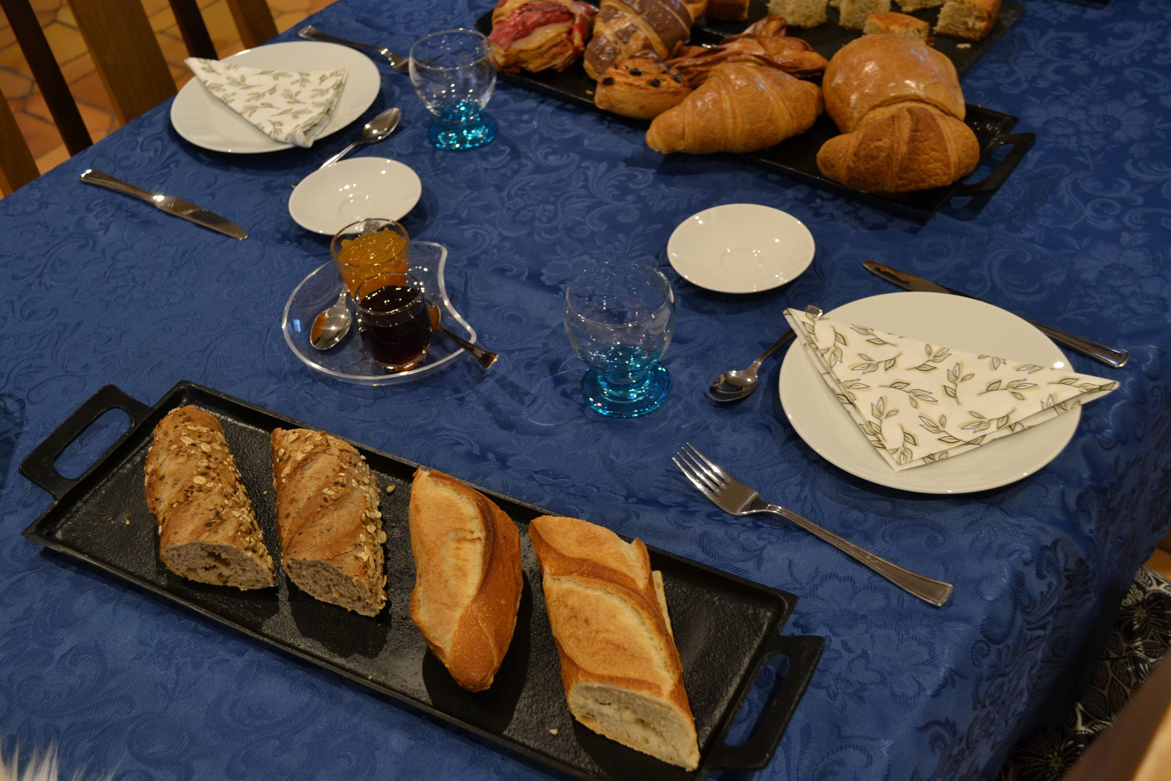 A table set with bread, croissants, and a plate of pastries.
