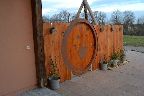 A rustic wooden gate with a large circular door, potted plants, and a metal structure above.