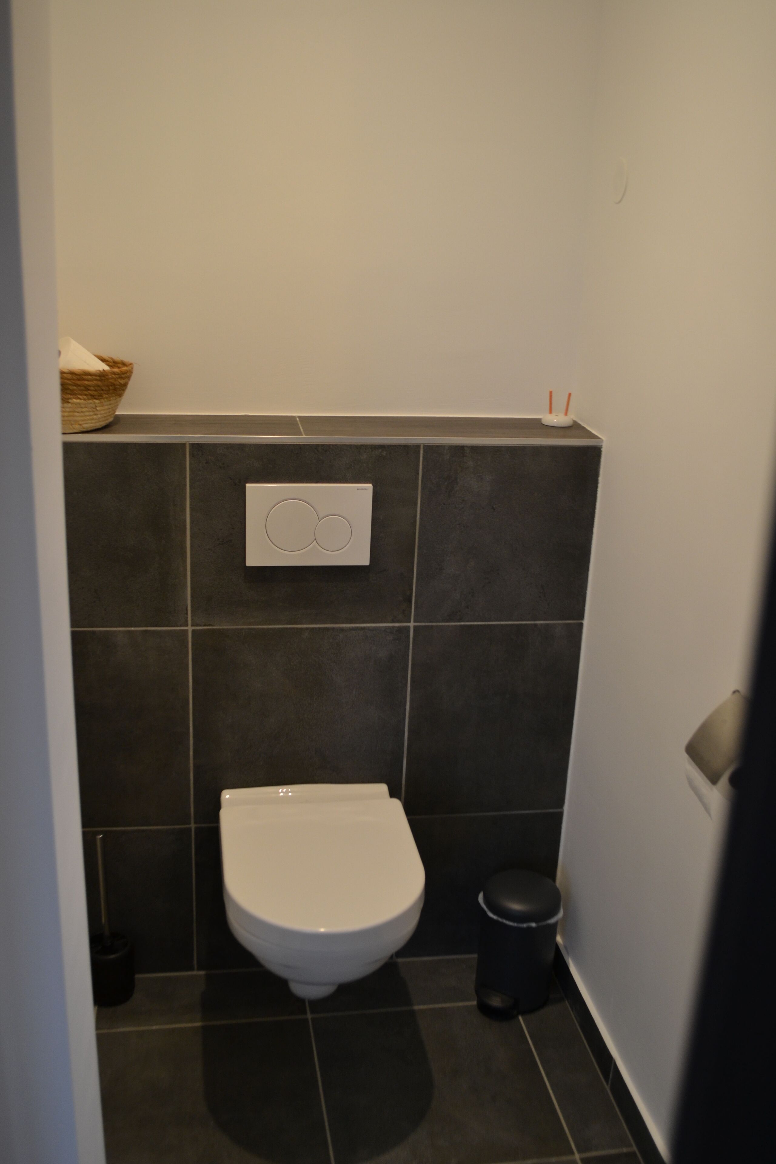 Et lille, moderne badeværelse med toilet, skraldespand og vægmonteret bidét.