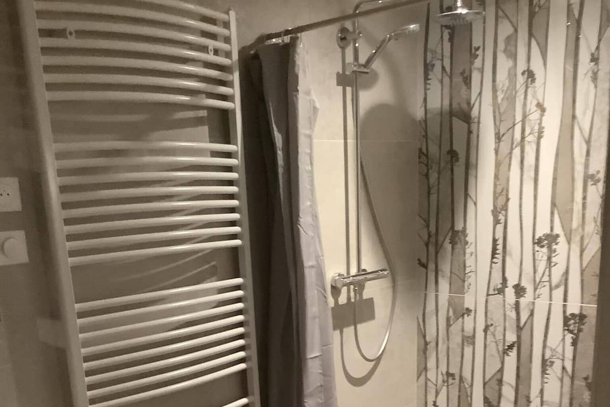 Une salle de bain avec une douche, un porte-serviettes et un meuble en bois.