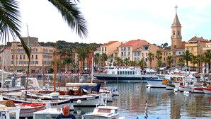Un port de plaisance où sont amarrés différents types de bateaux, entouré de bâtiments et de palmiers.