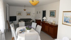 Un coin repas avec une table dressée pour quatre personnes, entourée de chaises. On peut voir une plante en pot sur la table.