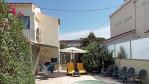 Un espace piscine doté d’un coin salon abrité, de mobilier d’extérieur et offrant une vue sur un ciel dégagé.