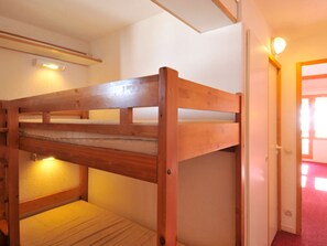 A bunk bed in a room with a door leading to another room.