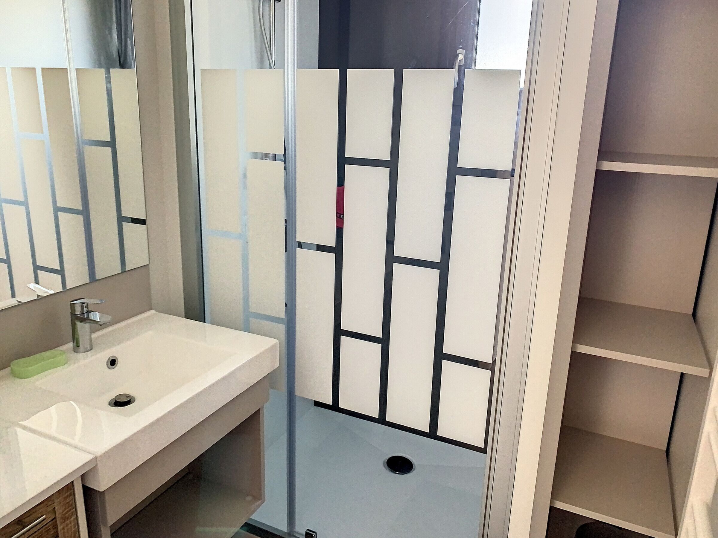 A bathroom with a white sink, a mirror, and a shower with a glass door.