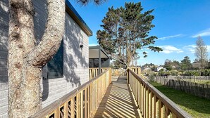 Une terrasse en bois menant à un bâtiment à la façade en pierre.