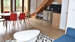 Une cuisine moderne avec un escalier en bois, un coin repas avec des chaises rouges et une grande fenêtre.