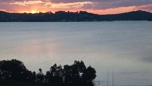 Ein ruhiger See bei Sonnenuntergang, mit einer entfernten Uferlinie und einem klaren Himmel.