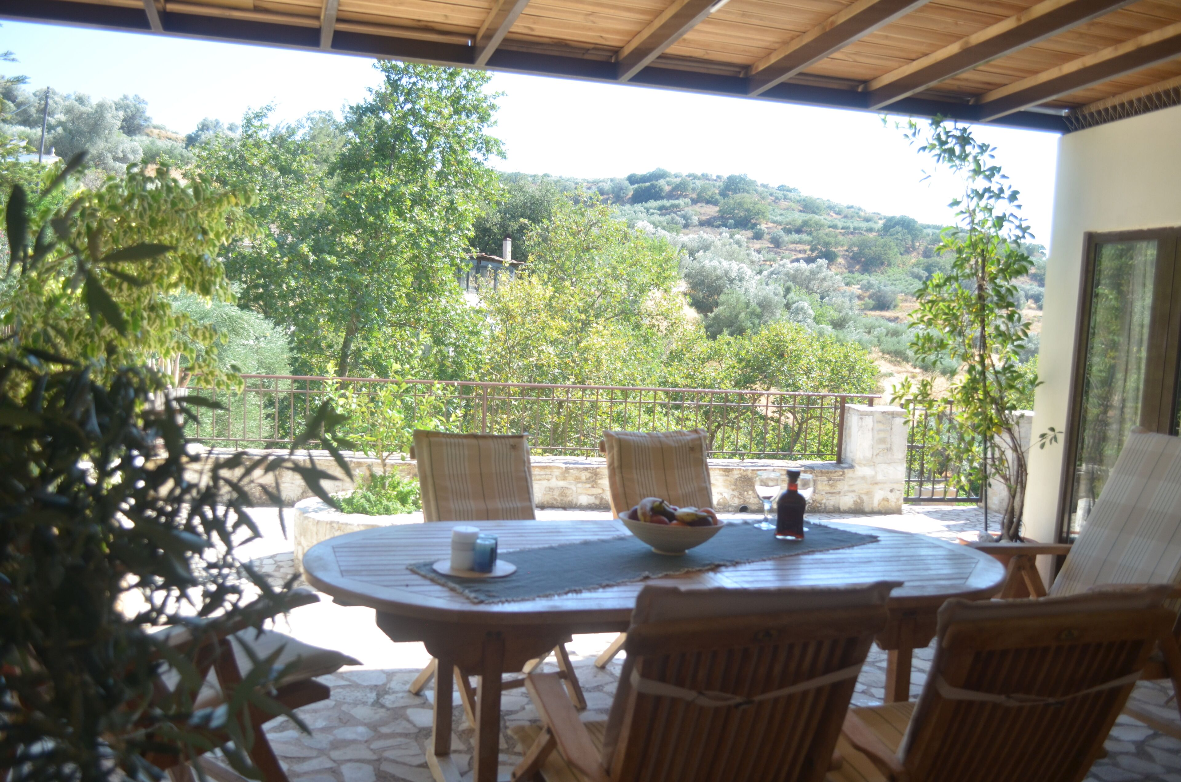 An outdoor patio with a round table, wicker chairs, and a bowl of fruit.