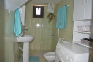 Baño con lavabo, inodoro, ducha y una pequeña ventana.