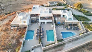 Un grand bâtiment à plusieurs étages doté d’un espace piscine, de coins salon extérieurs et d’un mur de soutènement en pierre.