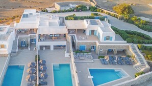 Un complexe hôtelier doté de plusieurs piscines, d’espaces extérieurs aménagés et d’une terrasse de piscine dont le sol est en pierre.