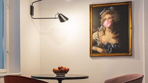 A room with a round table, two chairs, a painting on the wall, and a floor lamp.