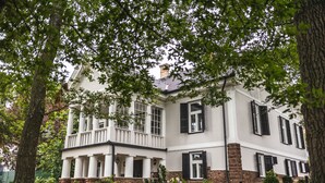 A two-story house with a white exterior, black shutters, and a stone foundation.
