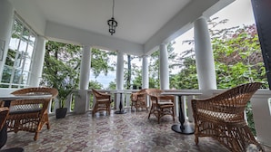 A covered patio with wicker furniture, large windows, and a patterned floor.